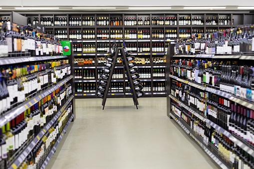 Moscow, Russia - November 17, 2019: Decoration with a wooden triangular counter and bottles of red wine in a supermarket. Wine store, bottles with alcoholic grape white wine on the shelves