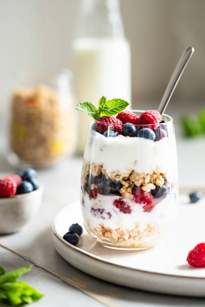 Glass of parfait made of granola, berries and yogurt. Glass of parfait made of granola, berries and yogurt on the table. Shot at angle, close up view, selective focus. yogurt parfait stock pictures, royalty-free photos & images