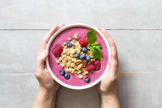 istock Female's hands holding smoothie bowl with granola and berries. 1264956537