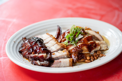 Chinese style roasted chicken and pork in a plate on top of table