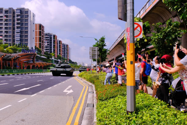 Singapore Mobile Column military parade travelling through Yishun Northpoint City on National Day Singapore National Day Aug09 2020. Spectators holding flags, waving, and taking photos from sidewalk as The Mobile Column military parade travels through Yishun town ndp stock pictures, royalty-free photos & images