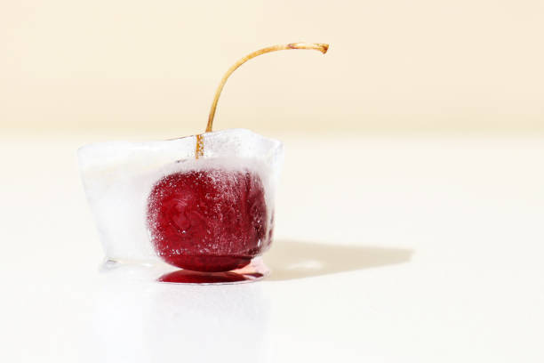 Macro shot of frozen cherries with ice crystals on the surface, isolated on white background.