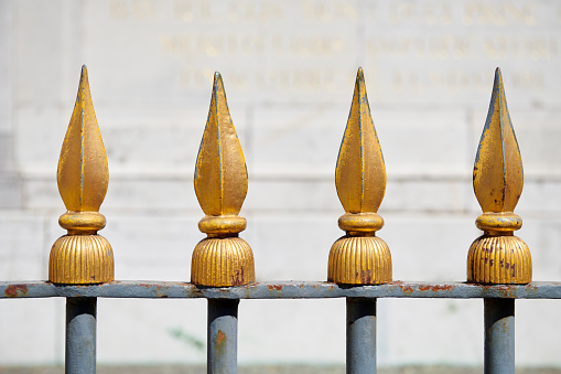 Four golden spikes, part of a fence.