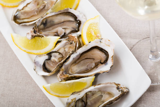 istock Tasty oysters with lemon on plate top view 1264966138