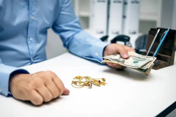 Photo of Man buying gold jewellry, pawn shop and us dollar banknotes