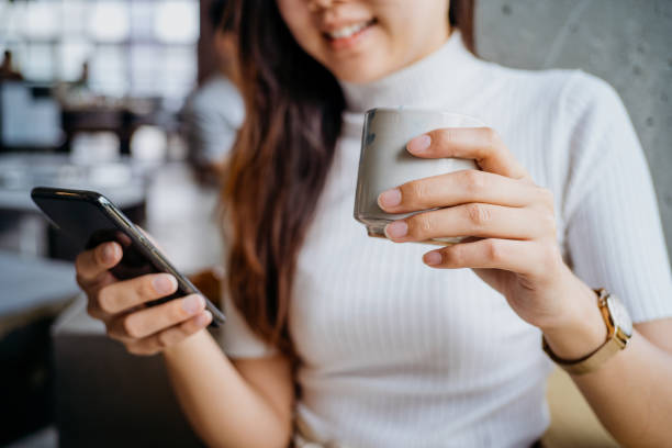 istock Young asian woman using phone and drinking coffee in cafe 1264968849