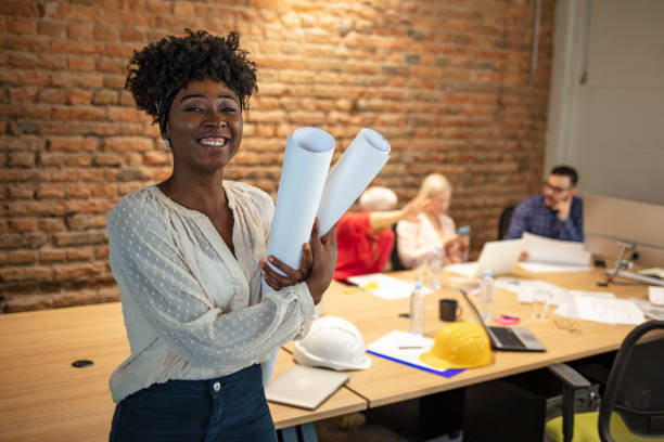 istock Black female architect smiling in busy office. 1264972503