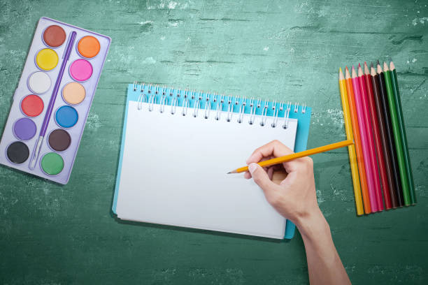 istock Hand with pencil writing in the book with a green background 1264973164