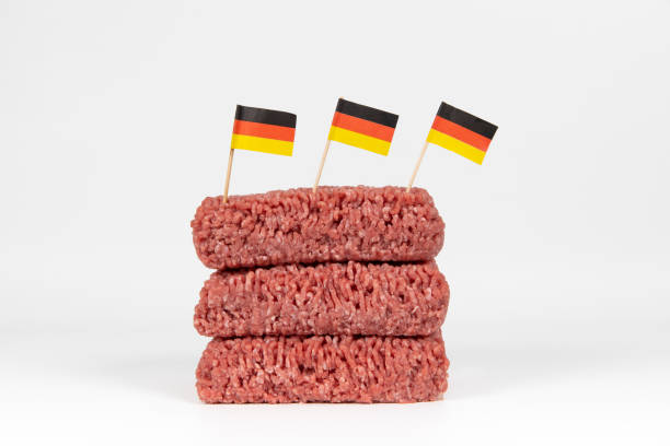 Minced meat with german flags A pile of fresh raw minced meat with three german flags sticking in it on white background alternative for germany photos stock pictures, royalty-free photos & images