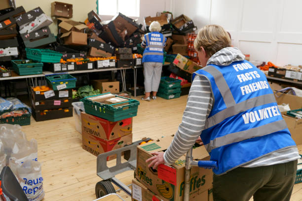 Volunteers unpacking food in a charity food bank centre 7th August 2020: Volunteers unpacking food that has been delivered for distribution to a charity food bank centre in the town of Penicuik, in Midlothian, Scotland. The women are wearing bright blue jackets to identify their volunteer roles in the centre, where emergency food parcels are given to those in crisis. A problem that has increased since the Covid-19 pandemic, with more people losing jobs and getting into financial difficulty. midlothian scotland stock pictures, royalty-free photos & images