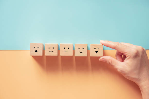 istock Customer service evaluation and satisfaction survey concepts. The client's hand picked the happy face smile face icon symbol on wooden cube. 1264981353