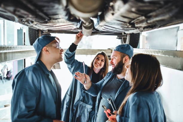 students examining car parts underneath car - trainee mechanic engineer student imagens e fotografias de stock