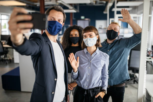 Startup team with face mask taking selfie in office