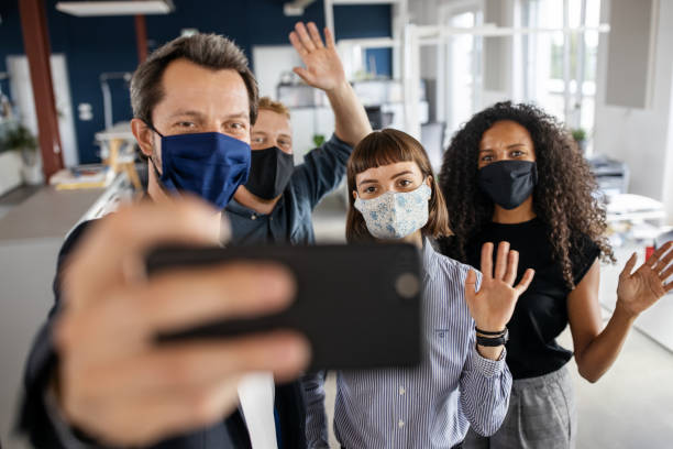 istock People with face masks back at work taking selfie 1264981584