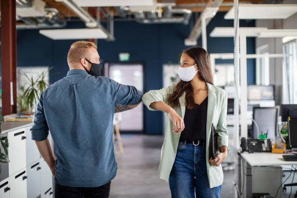 Business colleagues greeting with elbow in office Two business colleagues greeting with elbow in office. Business people bump elbows in office for greeting during covid-19 pandemic. social distancing photos stock pictures, royalty-free photos & images