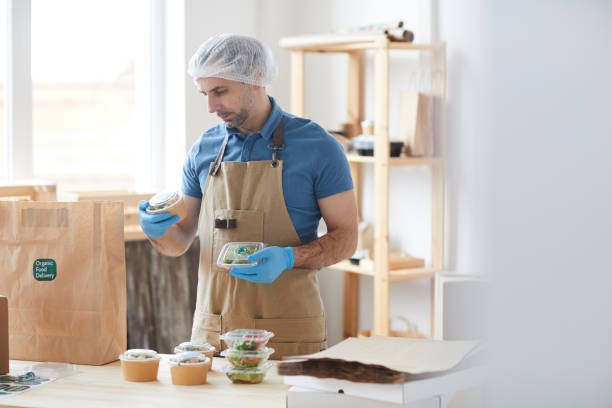 istock Male Worker Packing Orders at Food Delivery 1264983180