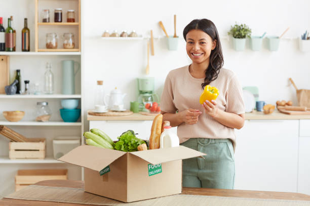 istock Smiling Woman Unpacking Box with Groceries 1264983244