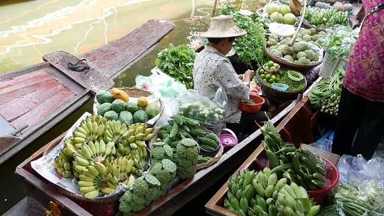 Bangkok, Thailand, - 13 July 2019: Lat Mayom floating market. Traditional classic khlong river canal, local women farmers, long-tail boats with fruits and vegetables. Iconic asian street food selling