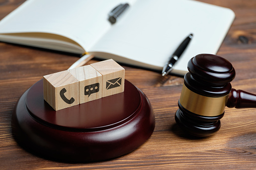 Phone, message and e-mail contact icons on wooden cubes with a row of judge hammer