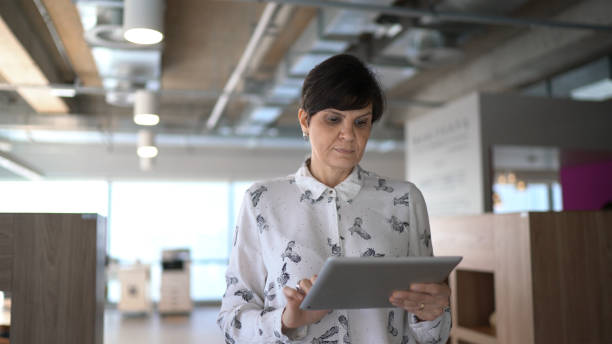 istock Businesswoman walking and using digital tablet at office 1264991335