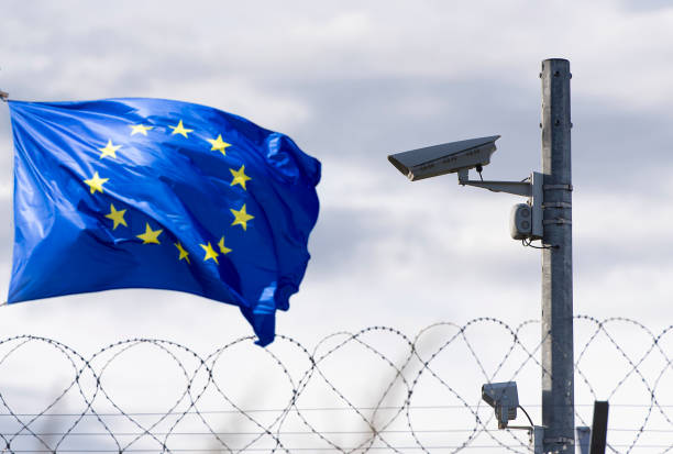 European union flag and EU border with surveillance camera and barbed wire, concept picture European union flag and EU border with surveillance camera and barbed wire, concept picture schengen agreement stock pictures, royalty-free photos & images