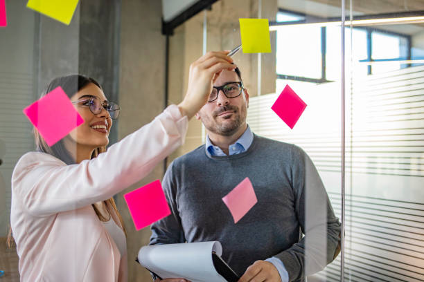 istock Business people looking at post it notes on notice board. 1264996145
