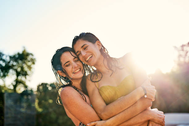 istock Young friends in bikinis hugging and laughing after a swim 1264996477