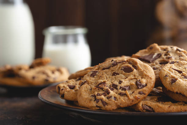 Chocolate Chip Cookies Closeup of chocolate chip cookies on a plate with glass of milk in background chocolate chip cookie stock pictures, royalty-free photos & images