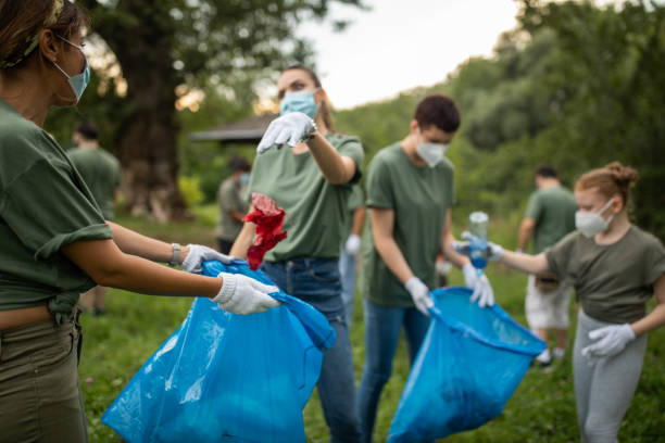 istock Female volunteer throwing garbage in garbage bag during environmental cleanup 1265004170