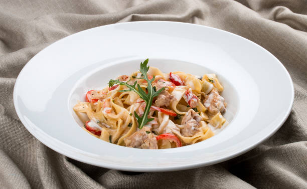 tagliatelle mit kaninchen und pfeffer, mit sahnesauce auf einem weißen teller. zum textilen hintergrund - hase wildfleisch stock-fotos und bilder