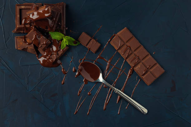 istock Chocolate pieces and mint leaves poured with liquid chocolate on the dark blue textured background. 1265004778