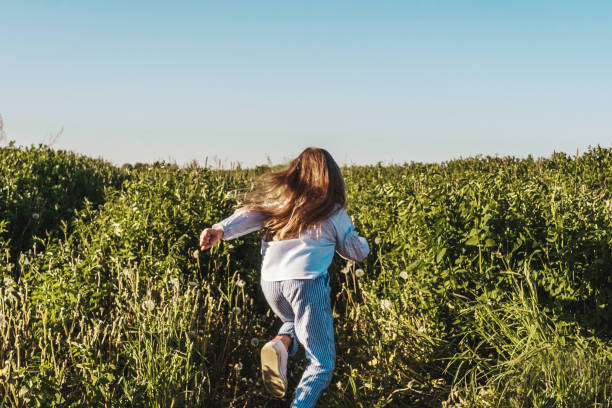 istock Happy girl run in field, back view. 1265006854
