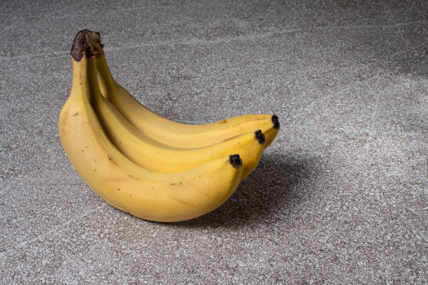 istock Bananas on a gray stone background. Three ripe yellow bananas. 1265008921