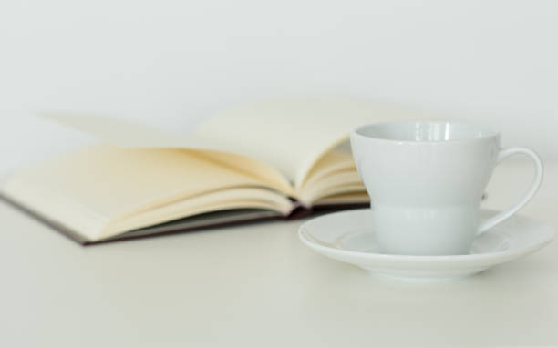 istock Open notebook with blank pages lying next to a coffee cup on a table isolated. 1265011963