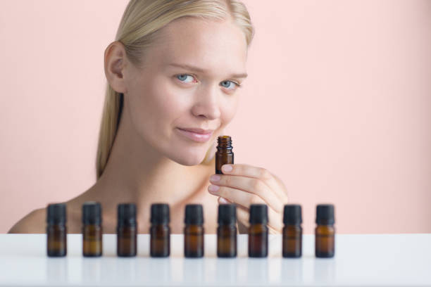 Essential oils. Beautiful woman displaying a row of small aroma therapeutic bottles while smelling.