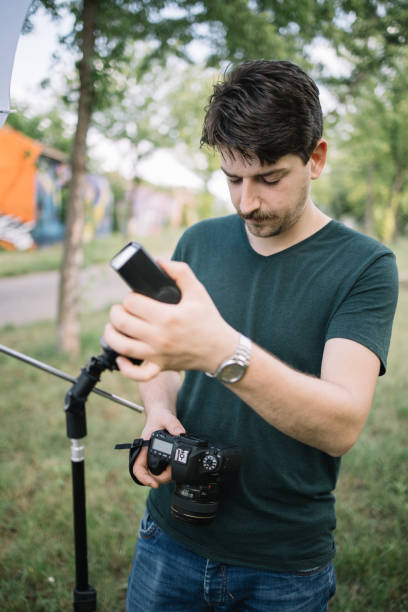 istock Man holding camera and preparing for outdoor photo session 1265012714
