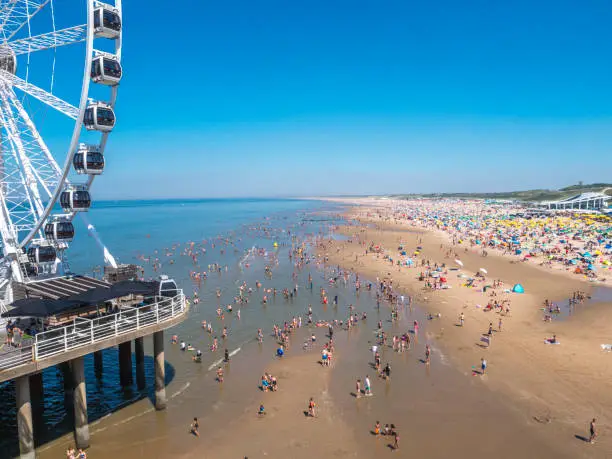 Beach of Scheveningen Netherlands in summer with ferris wheel.