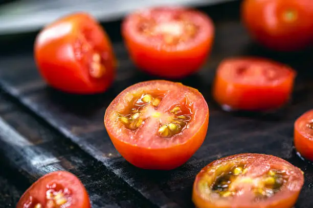 sliced "u200b"u200bred tomato to be used as a culinary ingredient on rustic wooden cutting board, vegan and organic cuisine