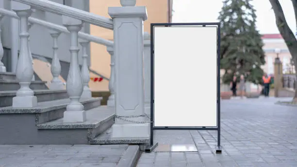 white mock-up in black metal frame stands on pavement of city street staircase with marble railing background outside