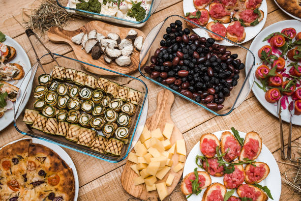 istock Different snacks with meat, cheese and vegetables on a wooden table at a banquet. Top down 1265019601