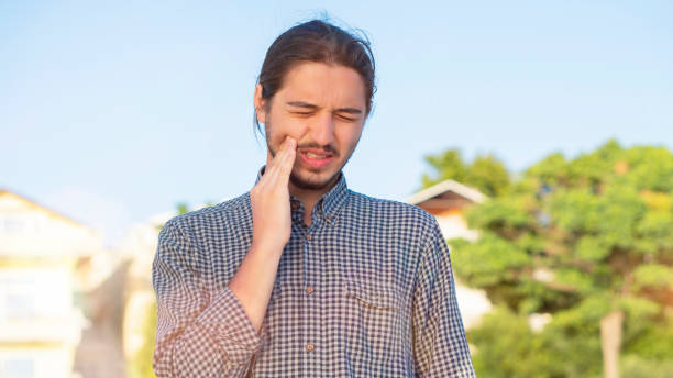 il suo viso distorto e le mani premute sulla guancia mentre sta vivendo un grave mal di denti e si preoccupa per questo. - t shirt male fashion model blank foto e immagini stock