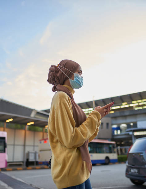 ライドシェアリングカーを待っているフェイスマスクを持つアジアの若い女性 - single line urban scene outdoors vertical ストックフォトと画像