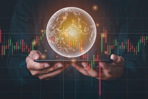 A man with tablet and a hand holding a globe graphic and stock chart Investment concepts, business concepts, technology concepts.