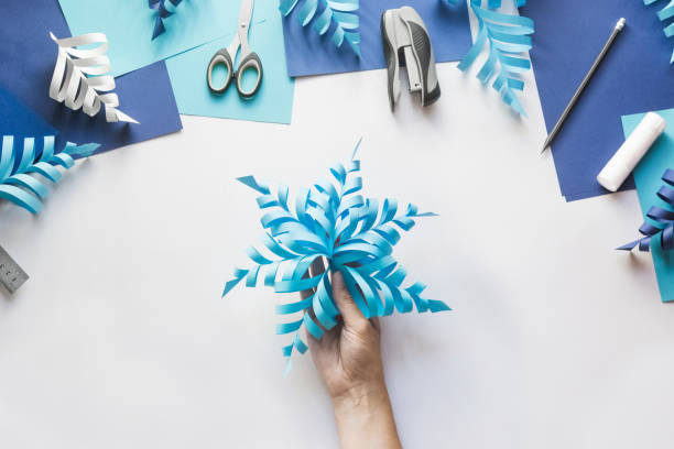 how to make paper beautiful christmas toy snowflake to decorate room with children at home. step by step instructions. top view. hands making diy winter craft project. step 11. enjoy ready toy - xmas toys snowflake imagens e fotografias de stock