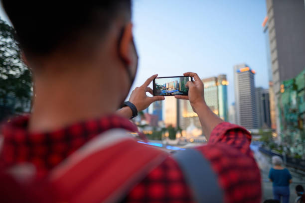 istock Asian young man taking picture with smartphone standing at the river waterfront 1265026642