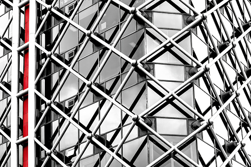 Architectural abstract. Generic modern building exterior in black and white with a touch of red. Horizontal tubular framework over glass.