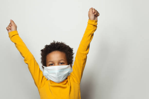 Portrait of happy black child boy in medical protective face mask holding hands up Portrait of happy black child boy in medical protective face mask holding hands up primary election photos stock pictures, royalty-free photos & images