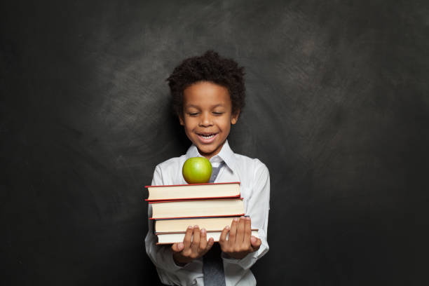 istock Happy black child holding books on black background 1265028922