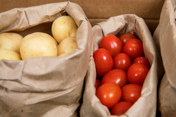 Fresh and organic potatoes and tomatoes in brown bag