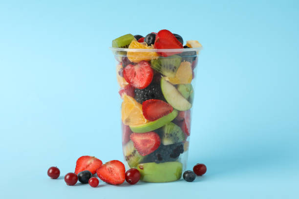 istock Fruit salad in takeaway cup on blue background, space for text 1265031005